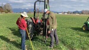 two people in a field with a tractor.