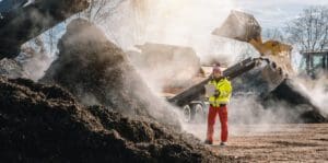 a person standing near piles of steaming compost.