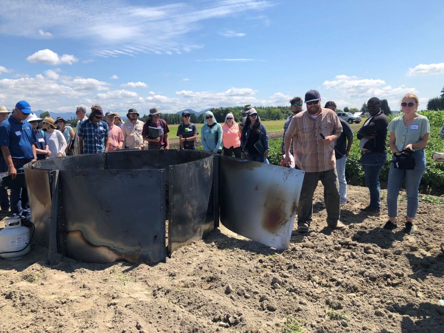 people standing around a biochar kiln.