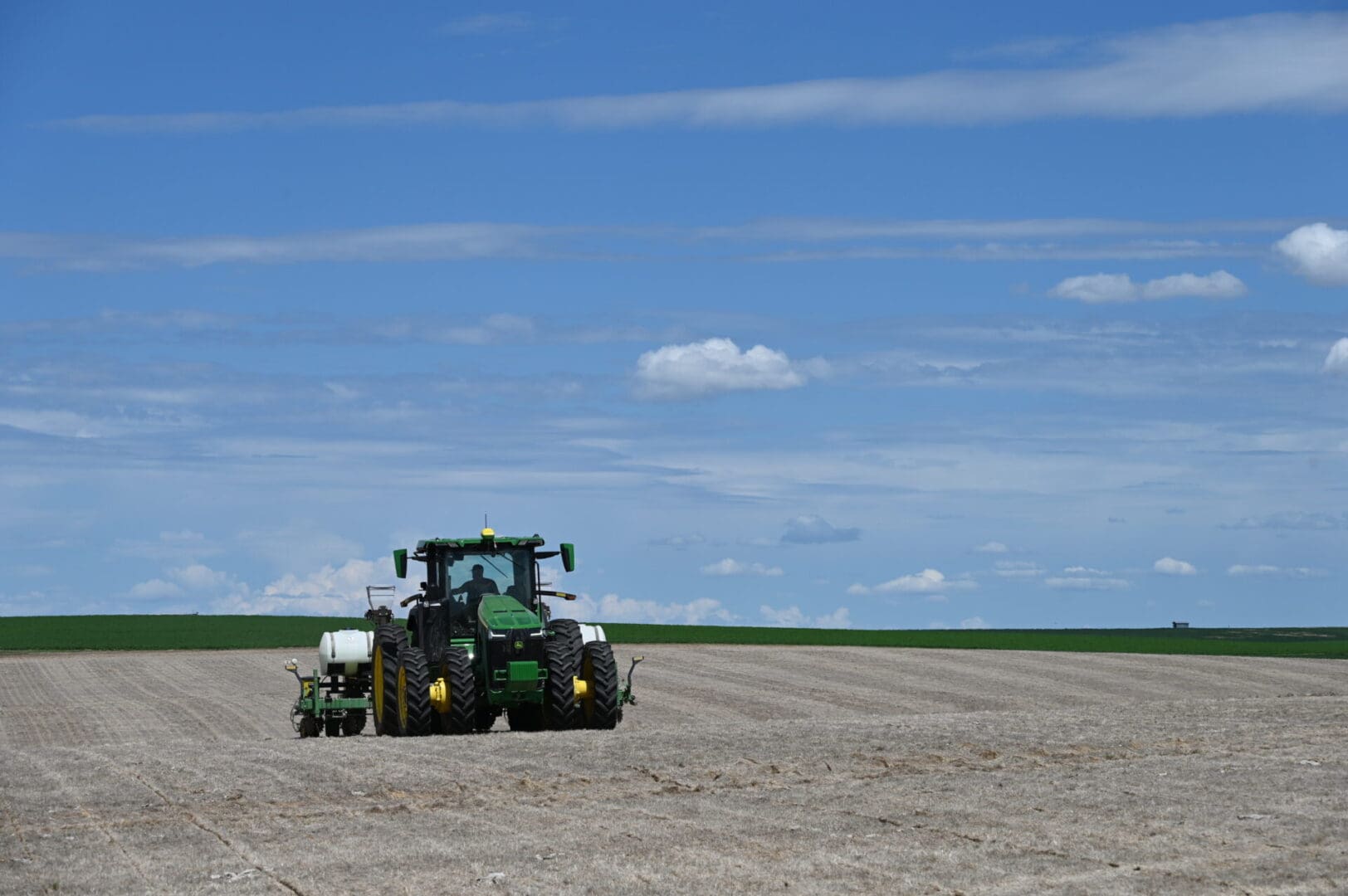 A tractor pulling a tank driving through a field.