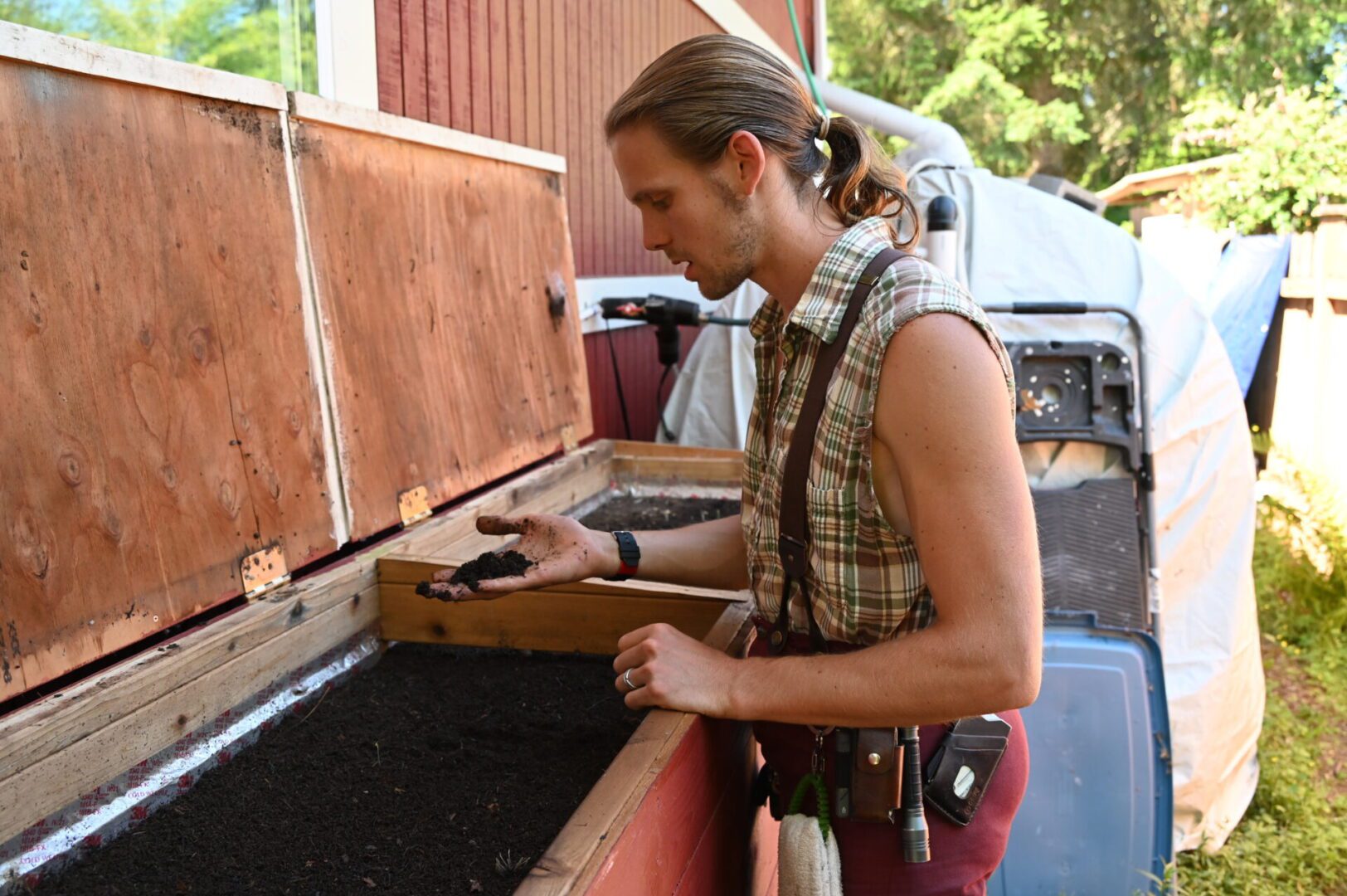 a person standing over a bin of dark compost.