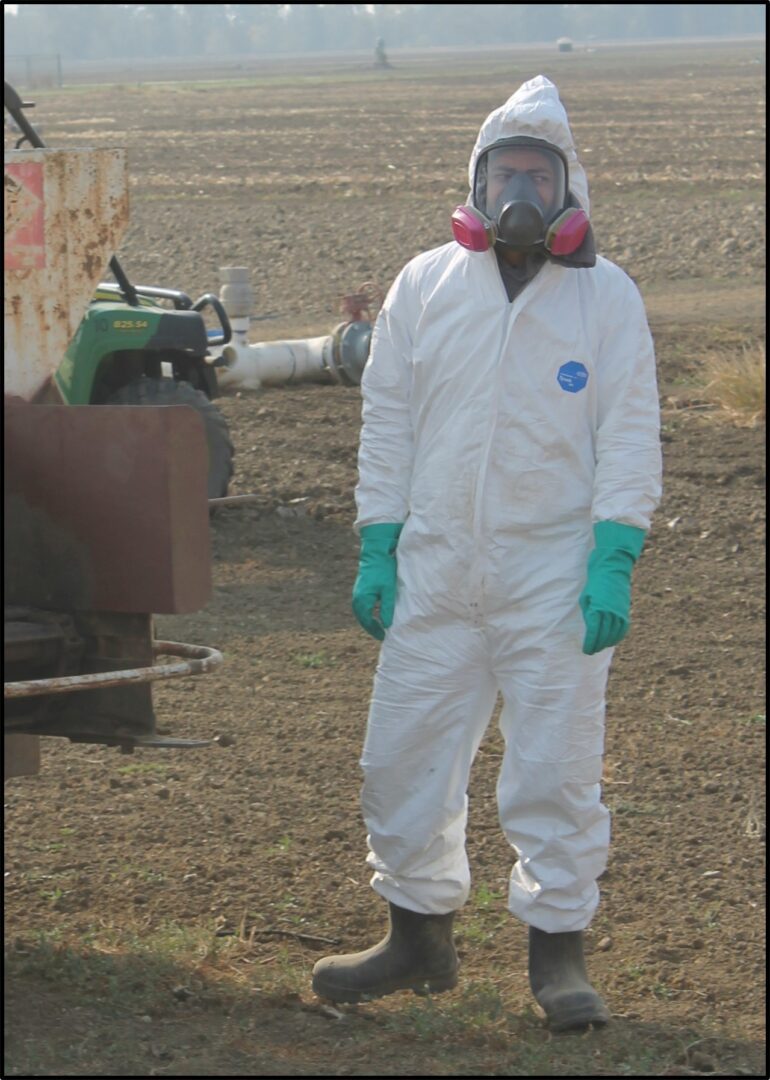 a person standing in a field with a white protective suit.