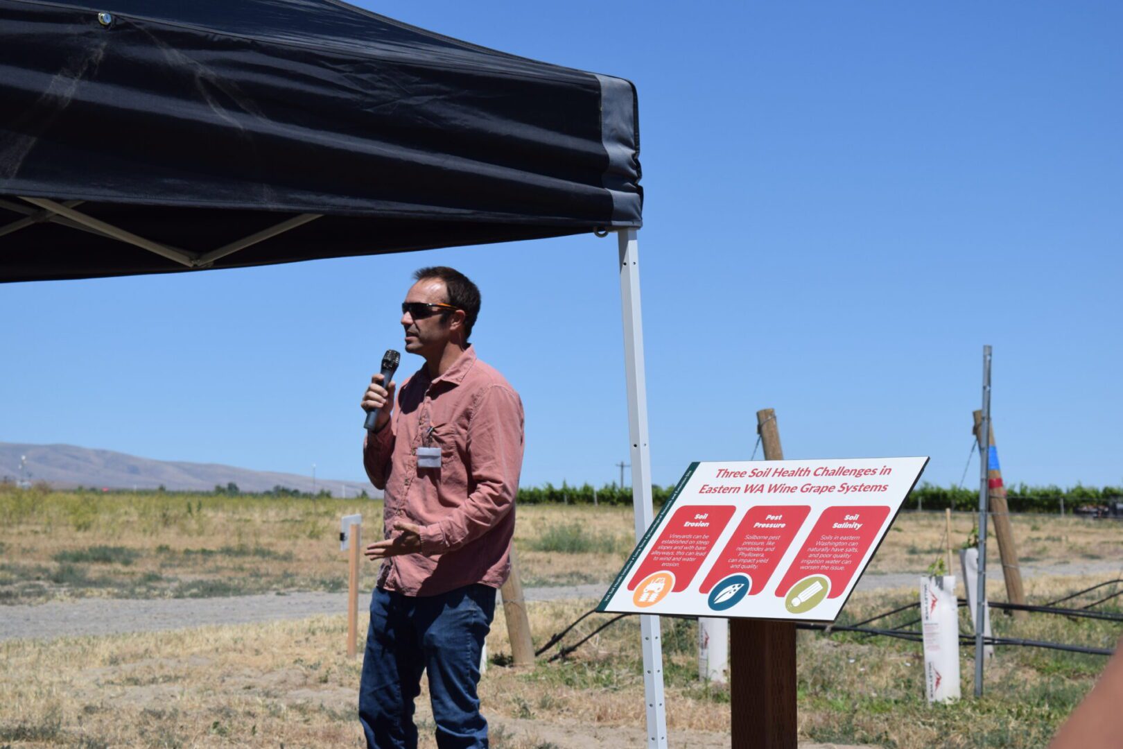 a person talking into a microphone standing in a field.