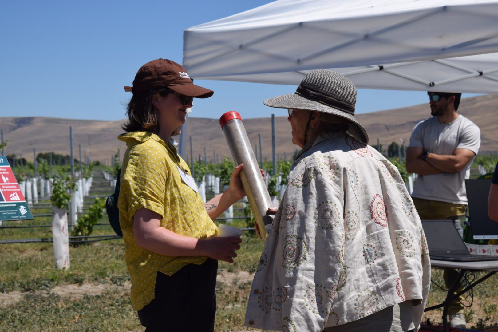 two people holding a tube with soil inside.