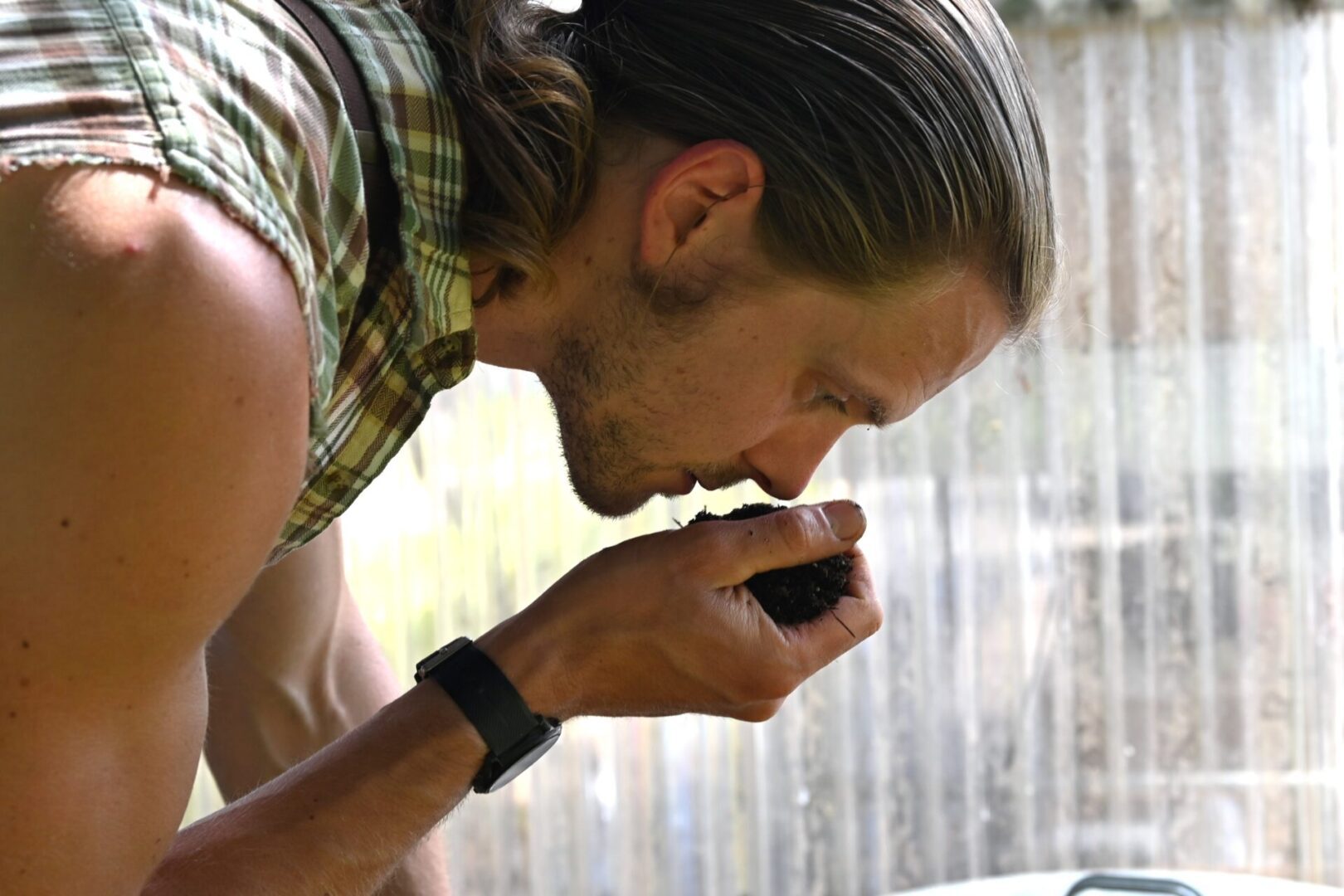 a person holding a handful of compost and smelling it.