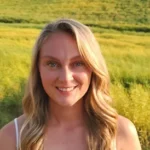 a person with long blonde hair standing in a field.